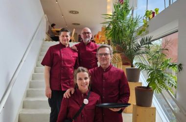 The K14 team poses for a group photo wearing dark red workwear.