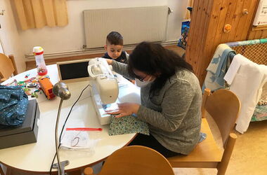 Eine Mutter näht konzentriert an einer Nähmaschine.