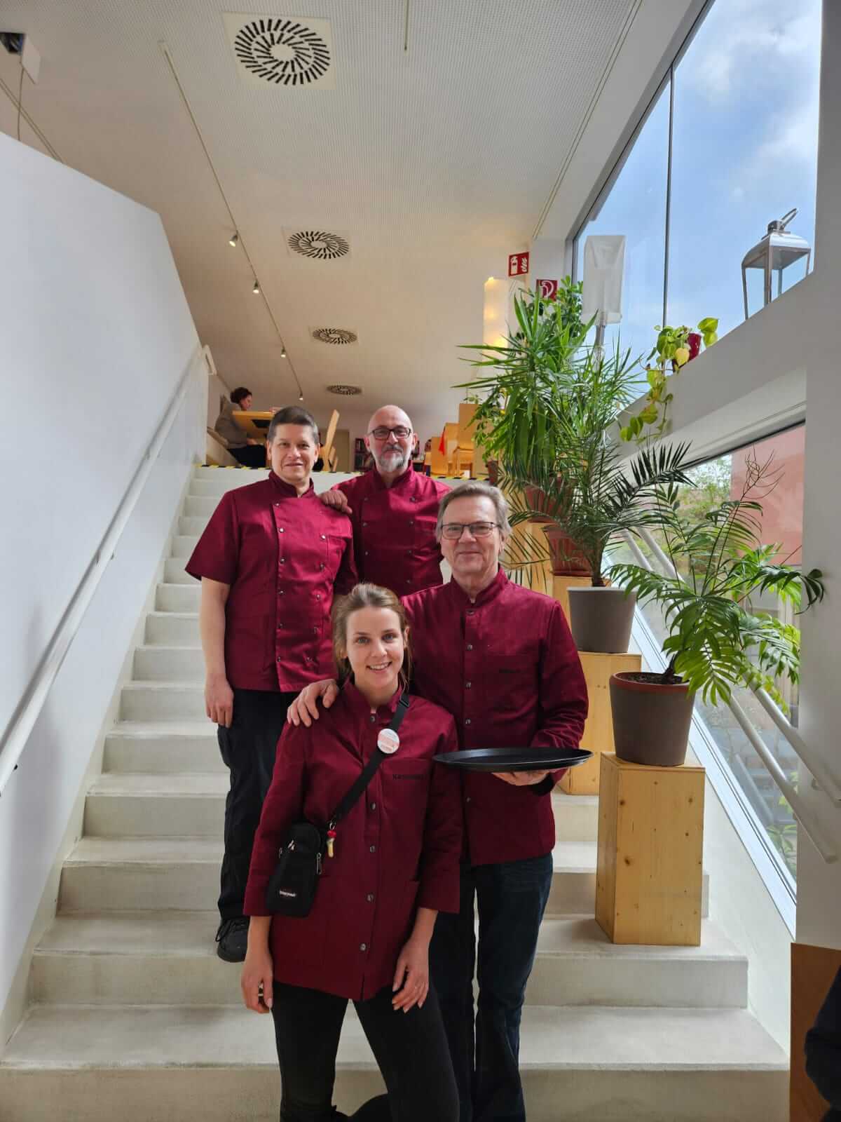 The K14 team poses for a group photo wearing dark red workwear.